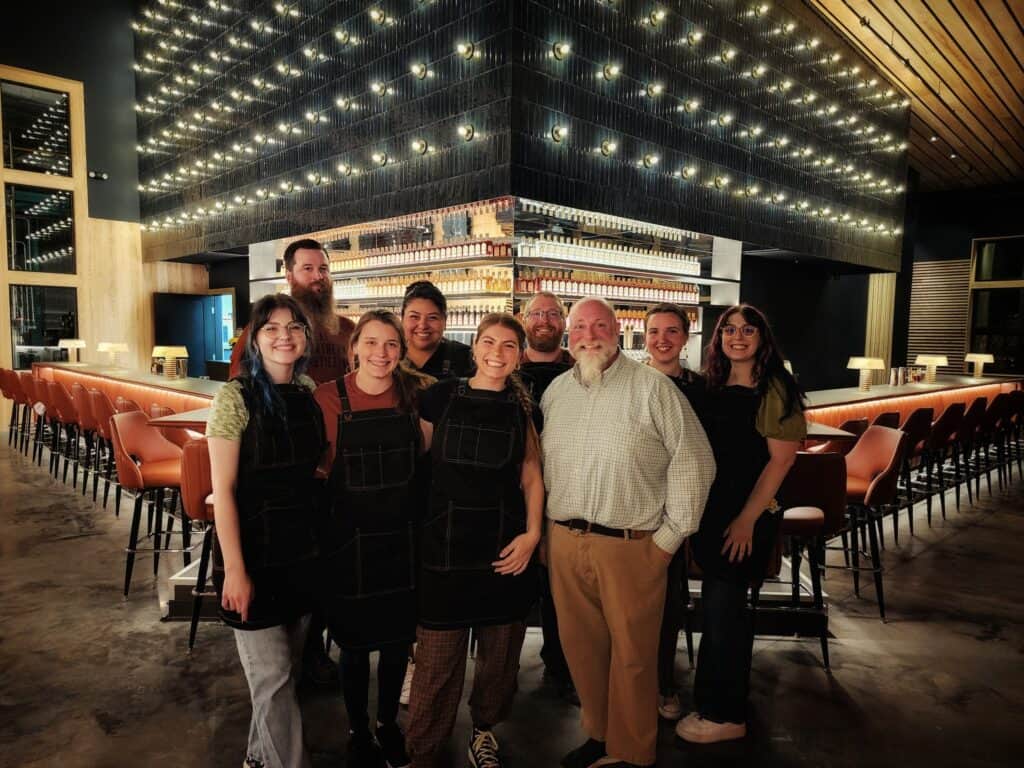 Group of people standing in front of a bar smiling at the camera.