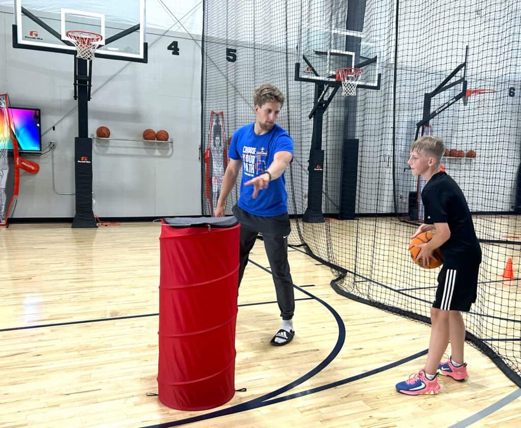 A man in a blue shirt coaches a boy in basketball.