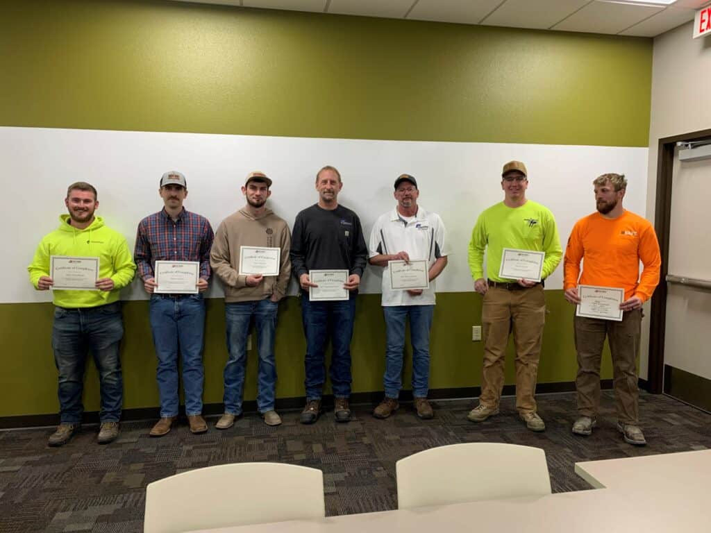 Group of men standing holding certificates and smiling at the camera.