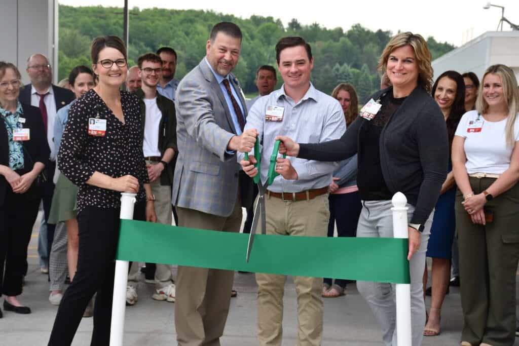 A group of people cutting a ribbon at a ribbon cutting ceremony.