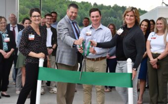 A group of people cutting a ribbon at a ribbon cutting ceremony.