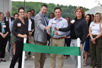 A group of people cutting a ribbon at a ribbon cutting ceremony.