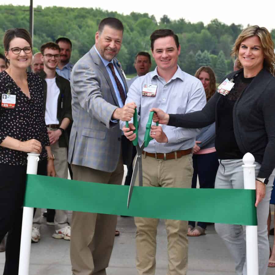 A group of people cutting a ribbon at a ribbon cutting ceremony.