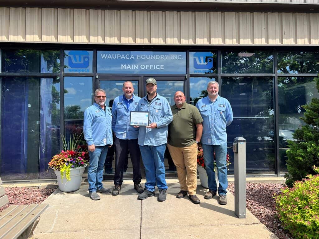 Five men standing in front of a building holding a certificate.