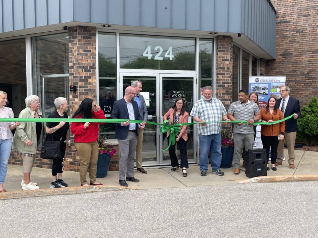 A group of people cutting a ribbon outside of a building.