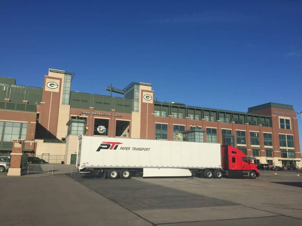 A large truck parked in front of a stadium.