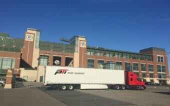 A large truck parked in front of a stadium.