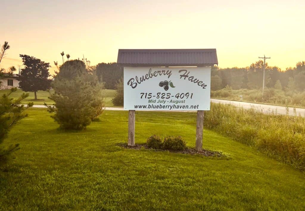 Sign for a berry farm in the grass.