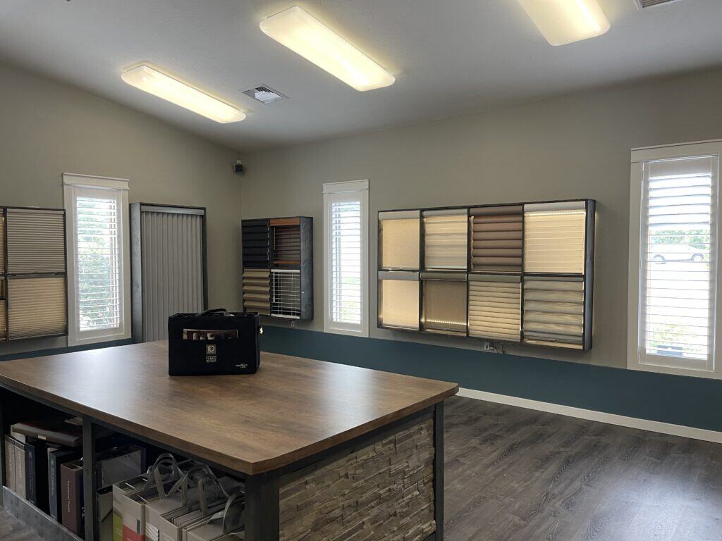 A room with a desk and a table with blinds.