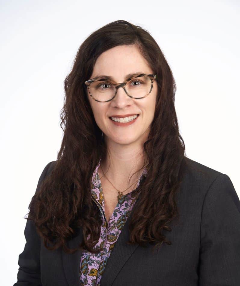 A woman in a business suit and glasses.