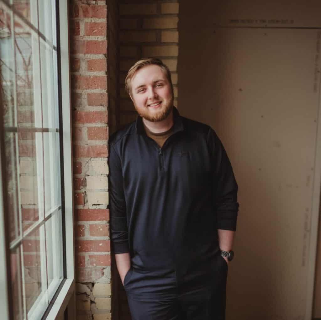 A man standing in front of a brick wall.