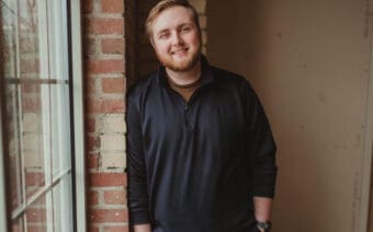 A man standing in front of a brick wall.