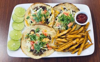 Three tacos and french fries on a white plate.