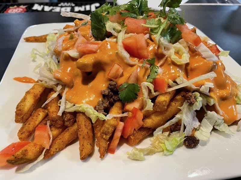A plate topped with fries and a sauce.