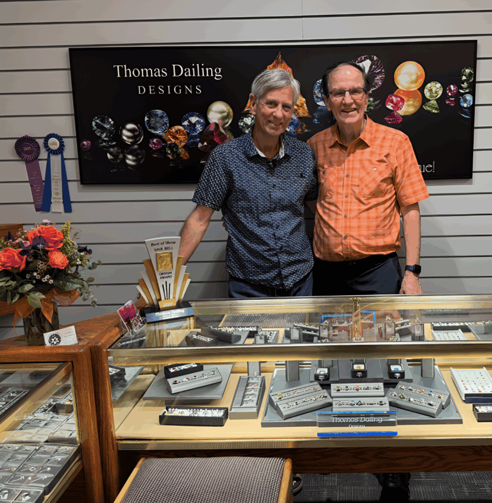 Two men standing in front of a jewelry display case.