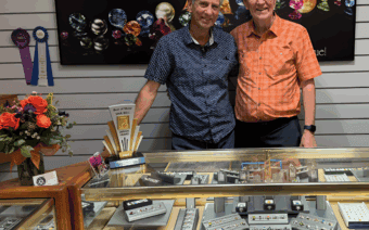 Two men standing in front of a jewelry display case.