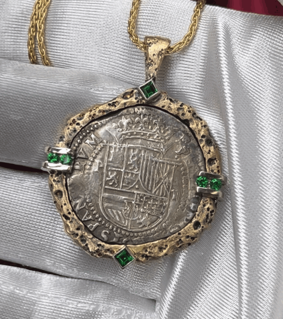 A silver coin with emeralds on it.