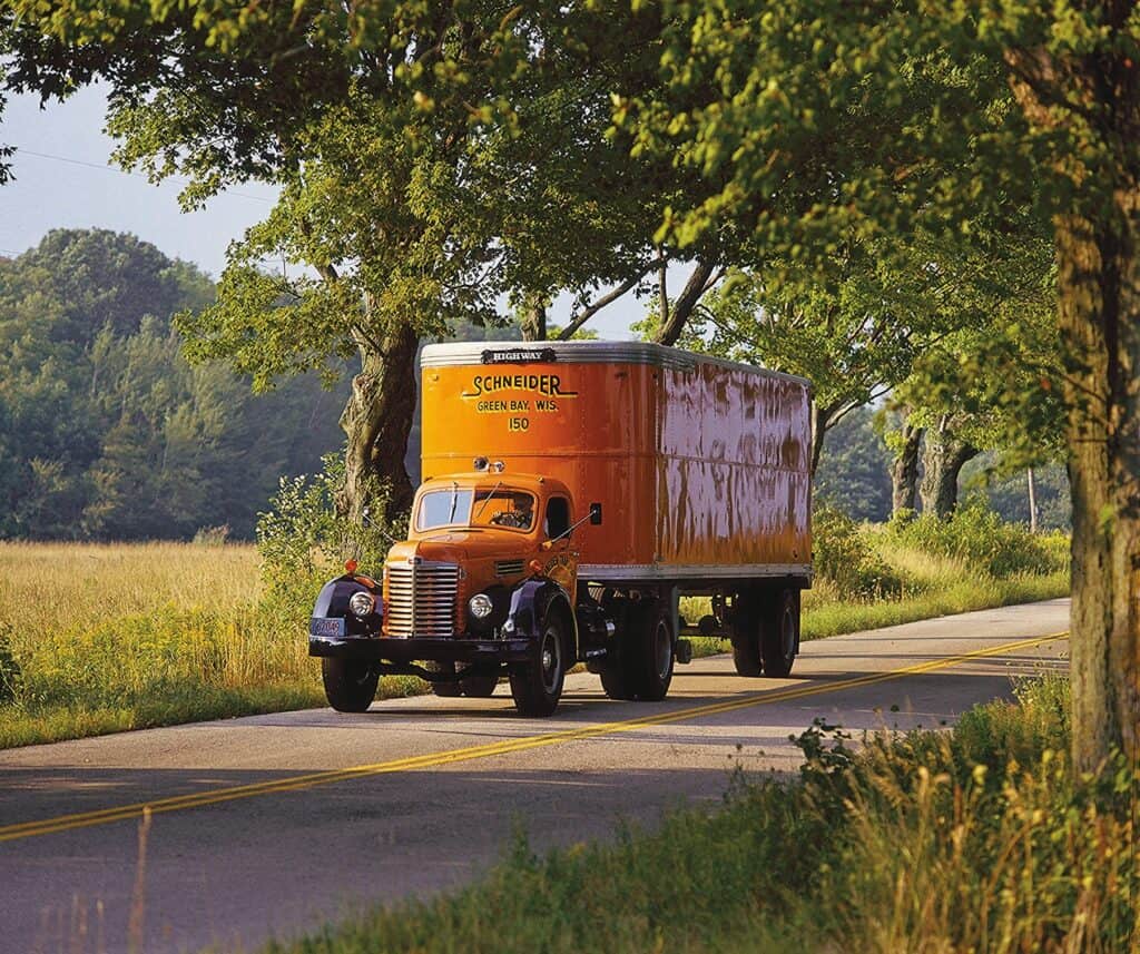 An orange truck driving down a country road.