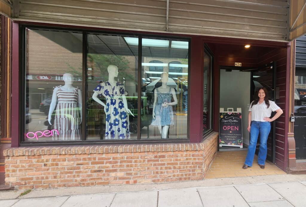 A woman standing outside of a clothing store.