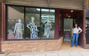 A woman standing outside of a clothing store.