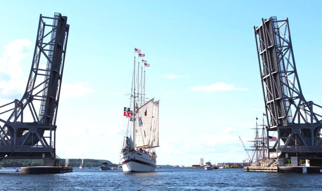 A sailboat is passing under a lift bridge.