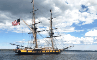 A tall ship with an american flag on the mast.