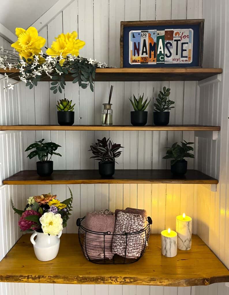 A shelf with plants and candles on it.